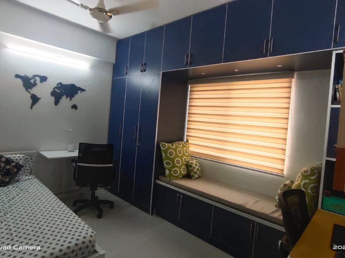 Kids bedroom with navy blue wardrobe, built-in study desk and cushioned window seat