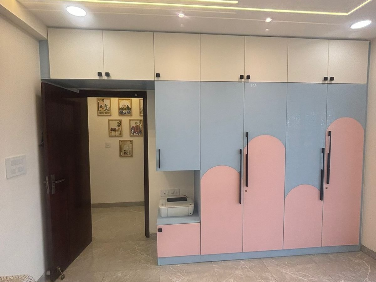 Pink and blue kids wardrobe with arched shutter design and study niche