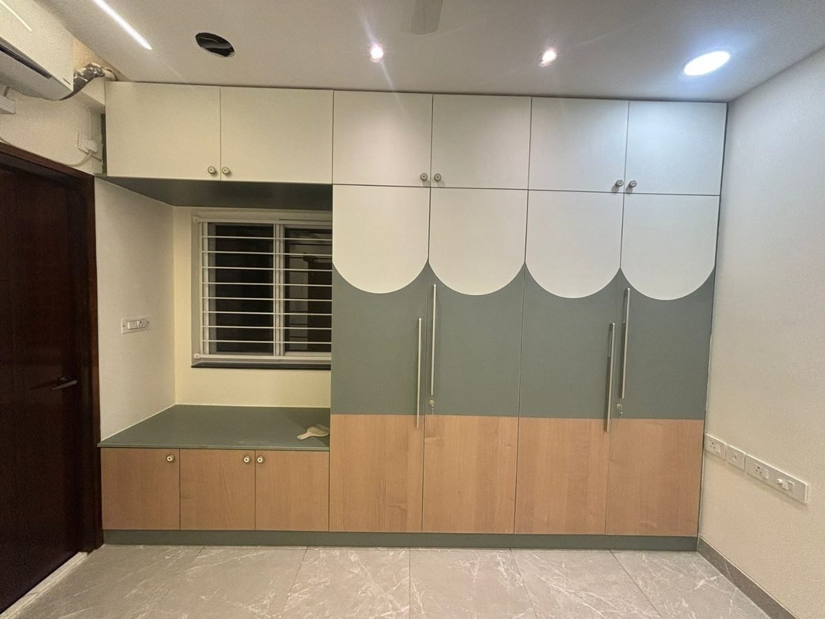 Sage green and oak wardrobe with arched shutters and a built-in window seat