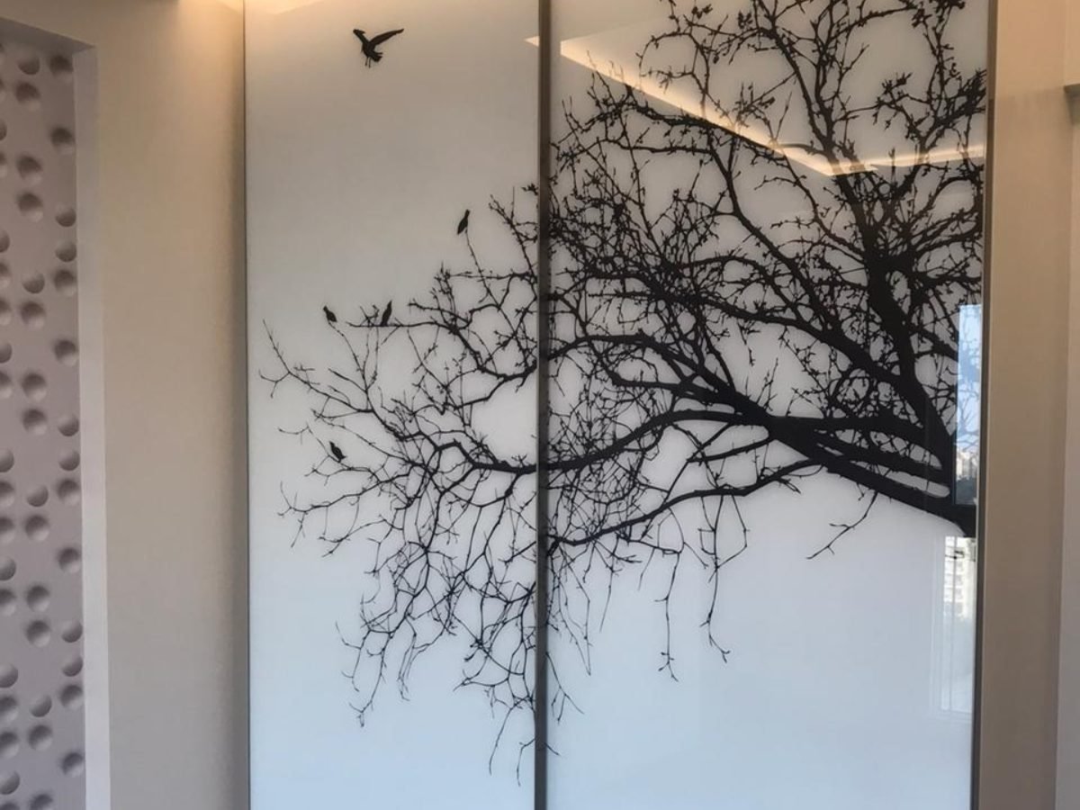 Sliding wardrobe with tree and bird artwork on lacquered glass shutters